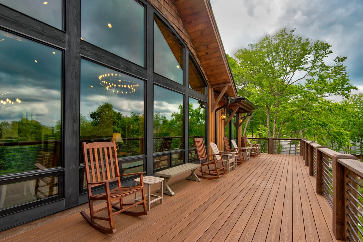 A welcoming wooden deck with large windows and classic rocking chairs, offering sunrise views and tranquil moments overlooking the trees. The deck serves as a transition between indoor comfort and outdoor adventure.