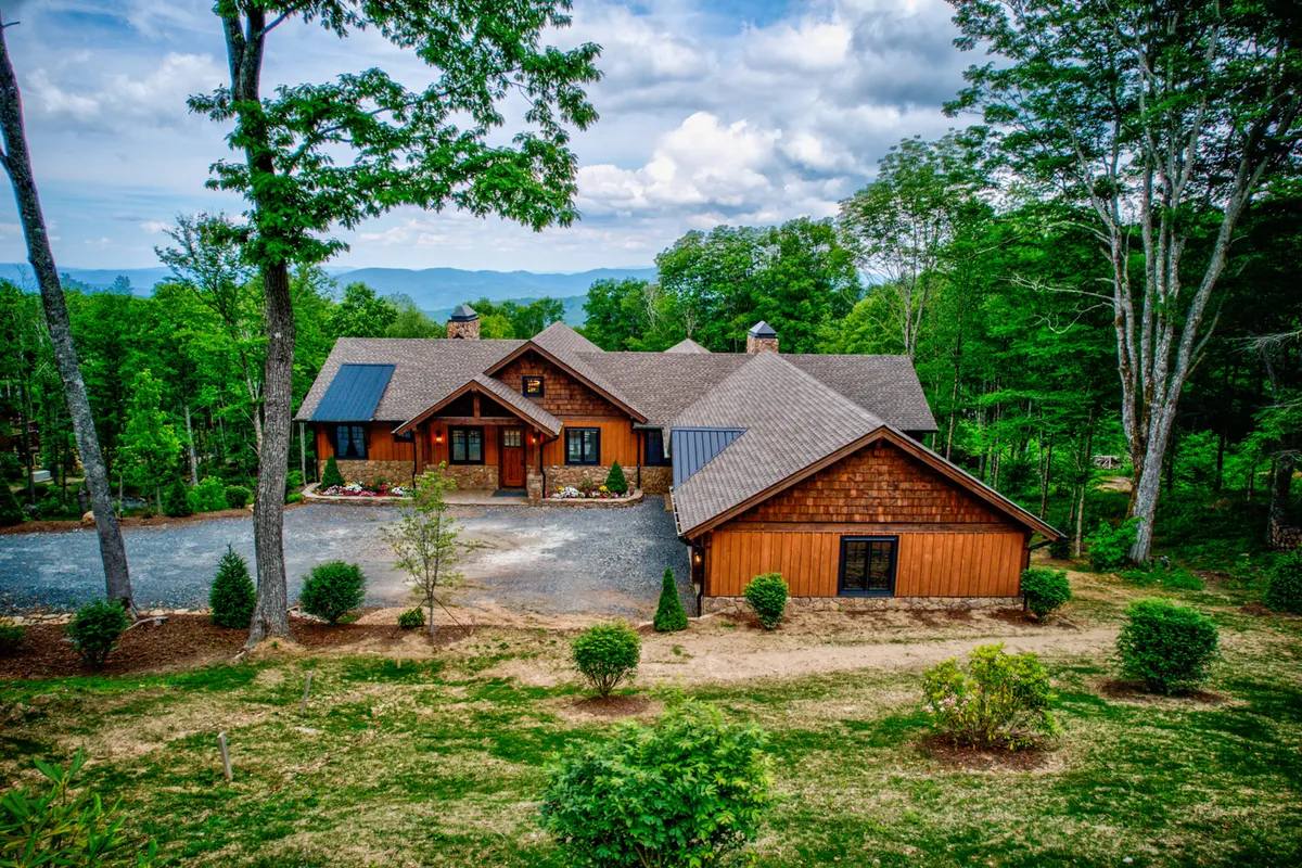 This image features the welcoming wooden exterior of the house set against a beautifully landscaped front yard, with the impressive backdrop of mountain views. The scene radiates tranquility and privacy, ideal for a group seeking an inspiring and secluded environment.